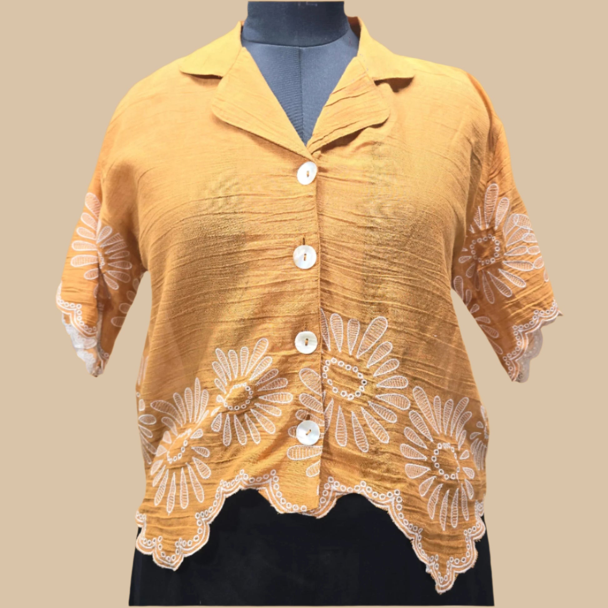 Yellow blouse with white floral embroidery on a gray background
